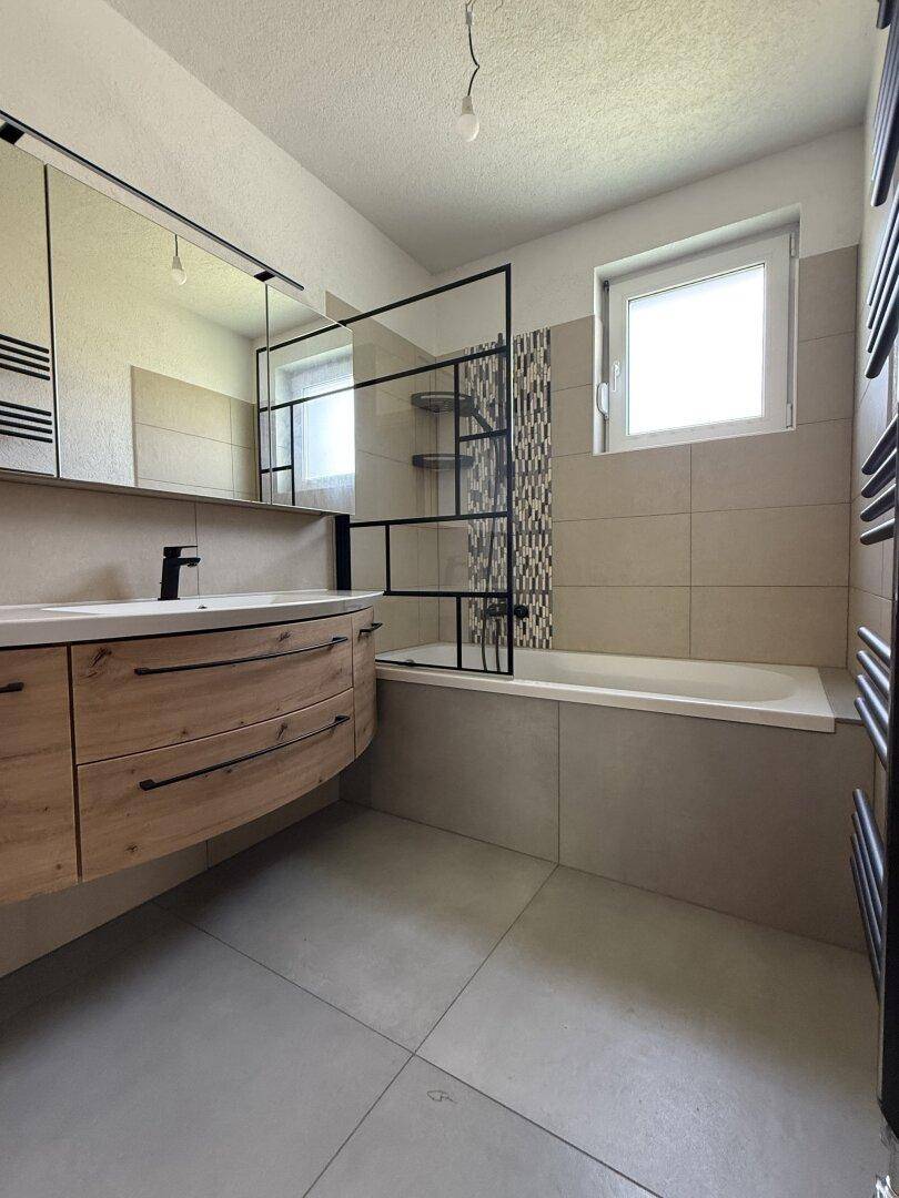 Modernes Badezimmer mit Holzwaschtisch, Badewanne und Duschabtrennung sowie Fenster.