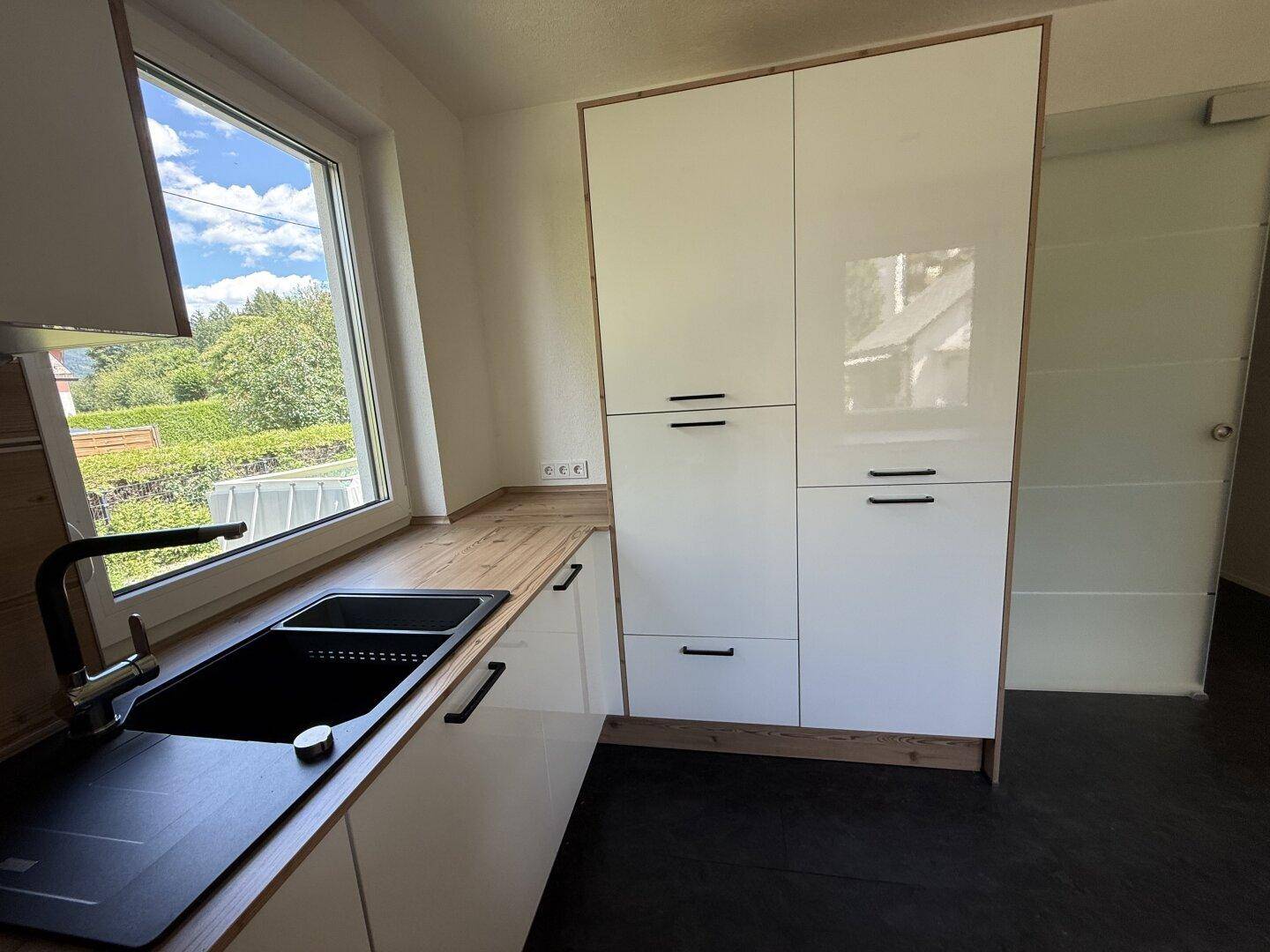 Helle Küche mit weißen Hochglanzschränken, integrierten Geräten und Holzdetails.