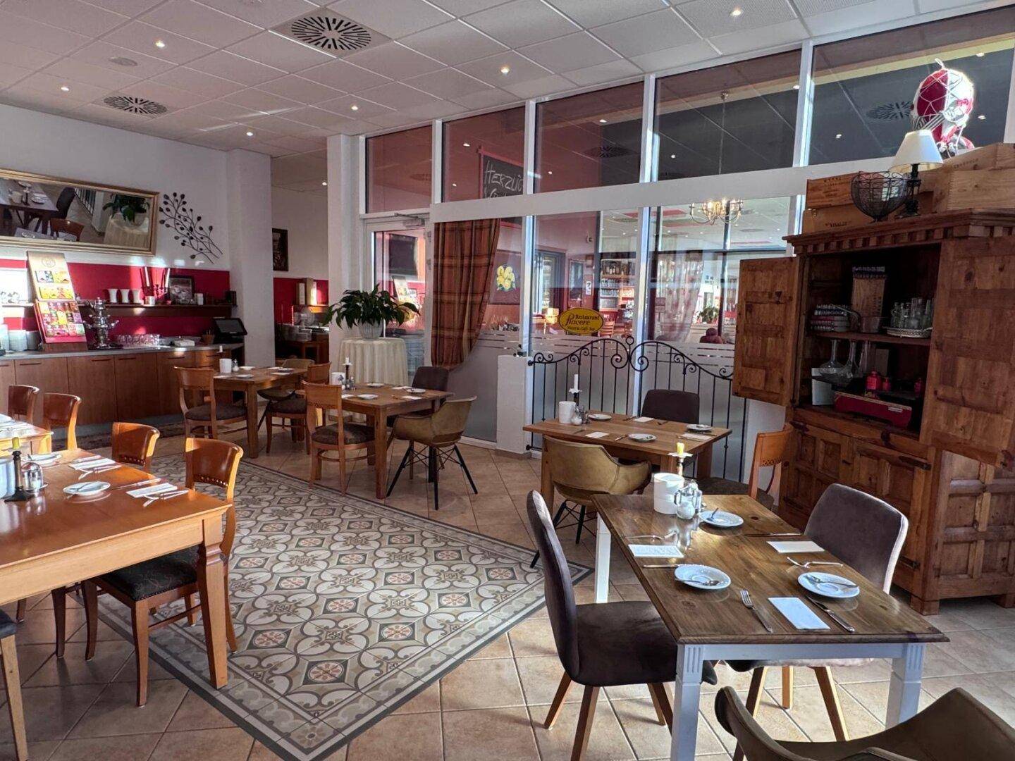 Weitläufiger Restaurantbereich mit mehreren gedeckten Tischen, Fliesenboden und einem Buffetbereich im Hintergrund.
