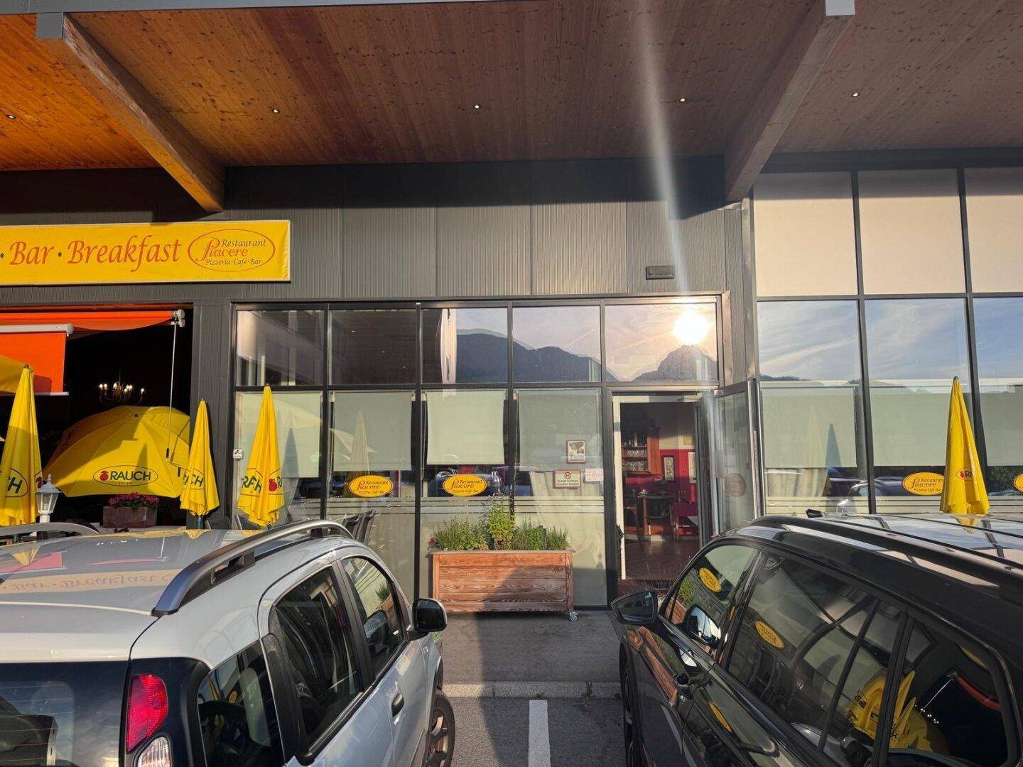 Außenansicht eines Geschäftsgebäudes mit großen Glasfenstern und einem Parkplatz davor bei Sonnenuntergang.