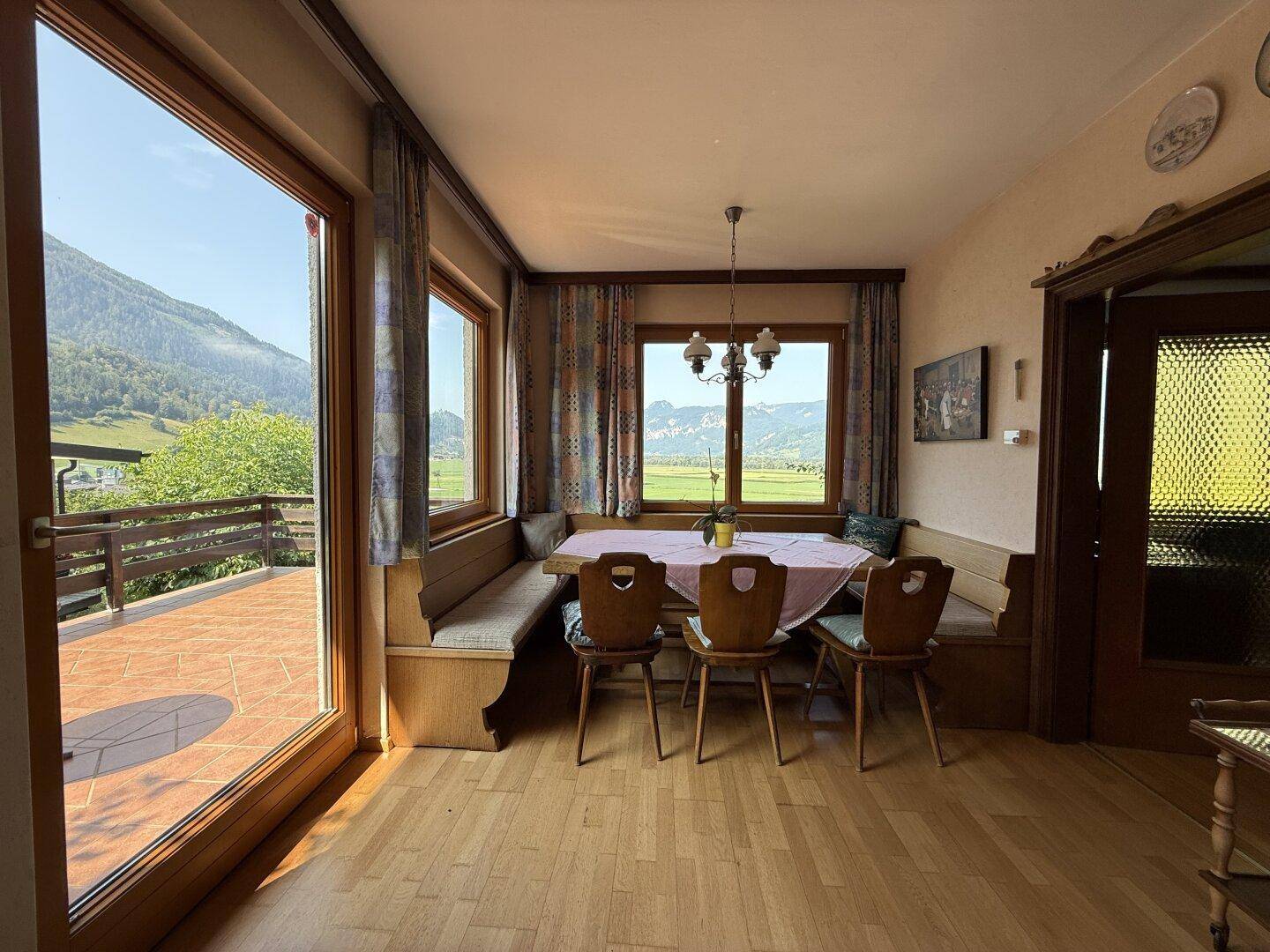Essbereich mit direktem Zugang zur gefliesten Terrasse und weitem Blick auf die Berglandschaft.