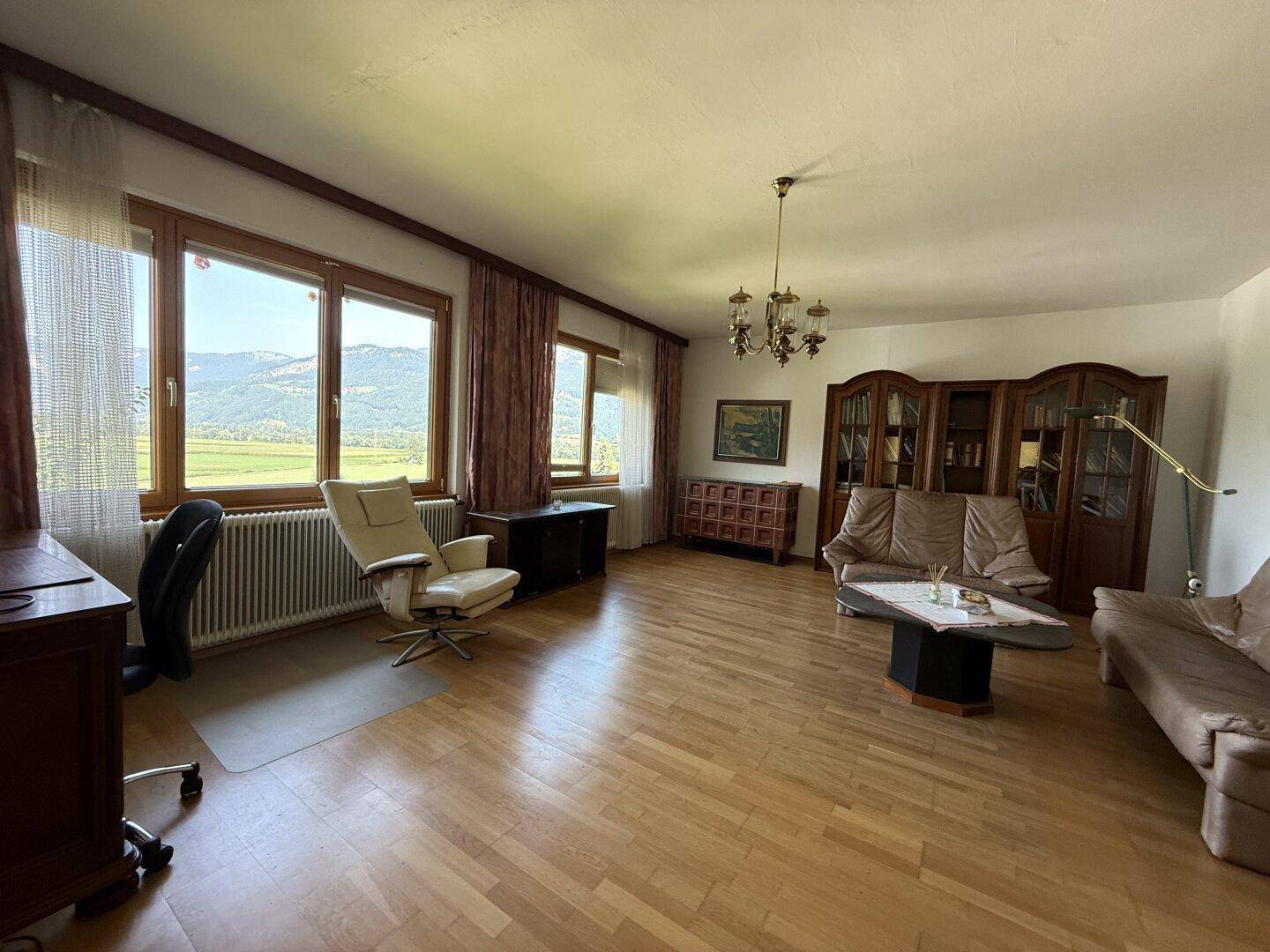 Geräumiges Wohnzimmer mit Parkettboden, bequemen Sofas und weitem Blick auf die Berge.