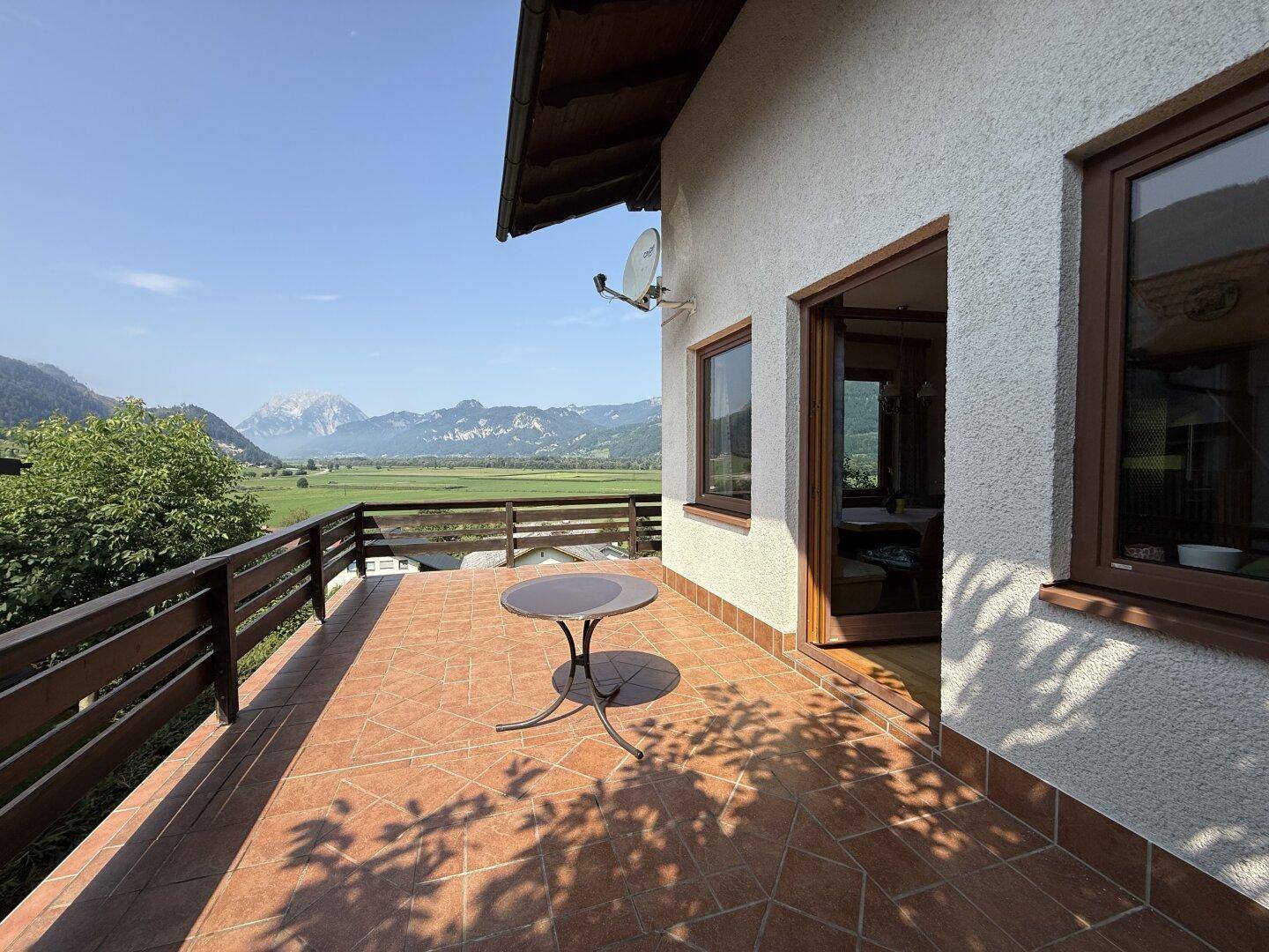 Geräumige geflieste Terrasse mit kleinem Tisch und herrlichem Blick auf die Bergwelt.