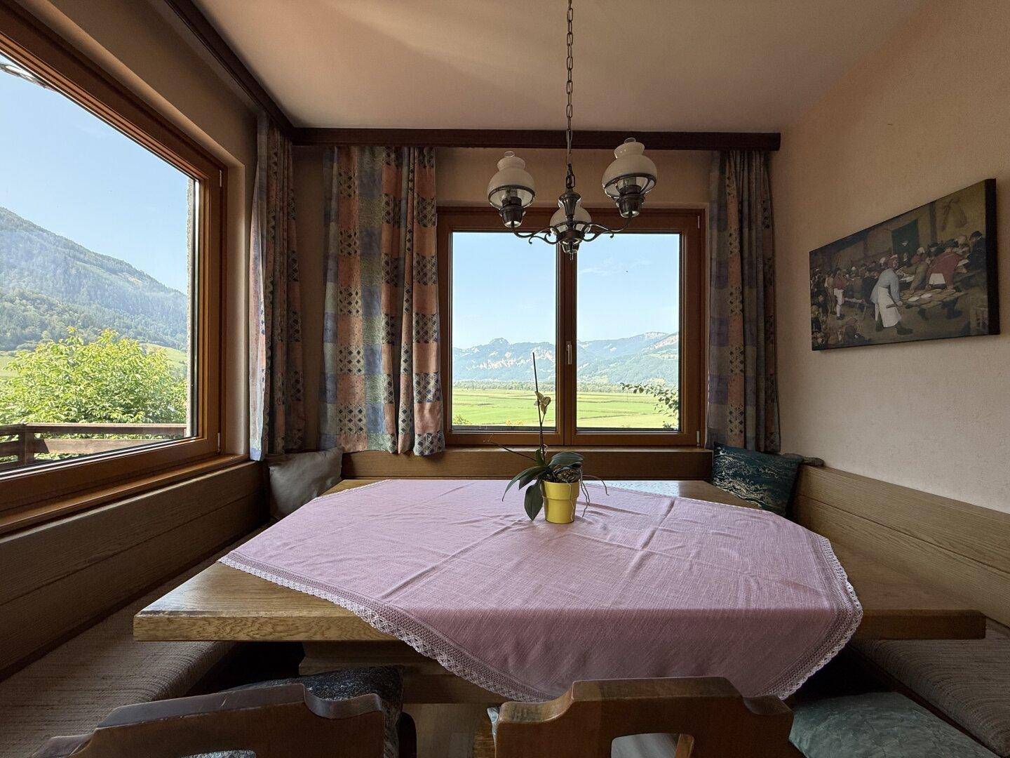 Heller Essbereich mit großer Eckbank und weitem Panoramablick auf die Berge und Felder.