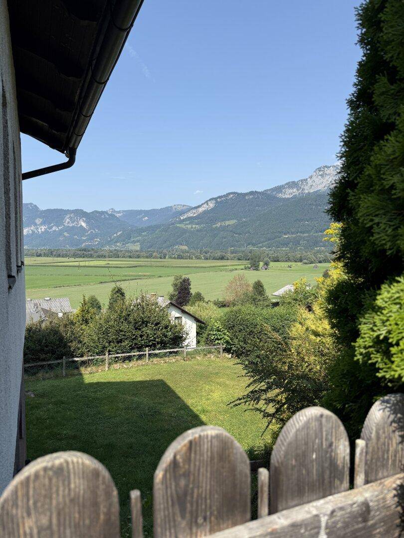 Kleiner Gartenbereich mit Holzzaun und Ausblick auf die grüne Tal- und Berglandschaft.