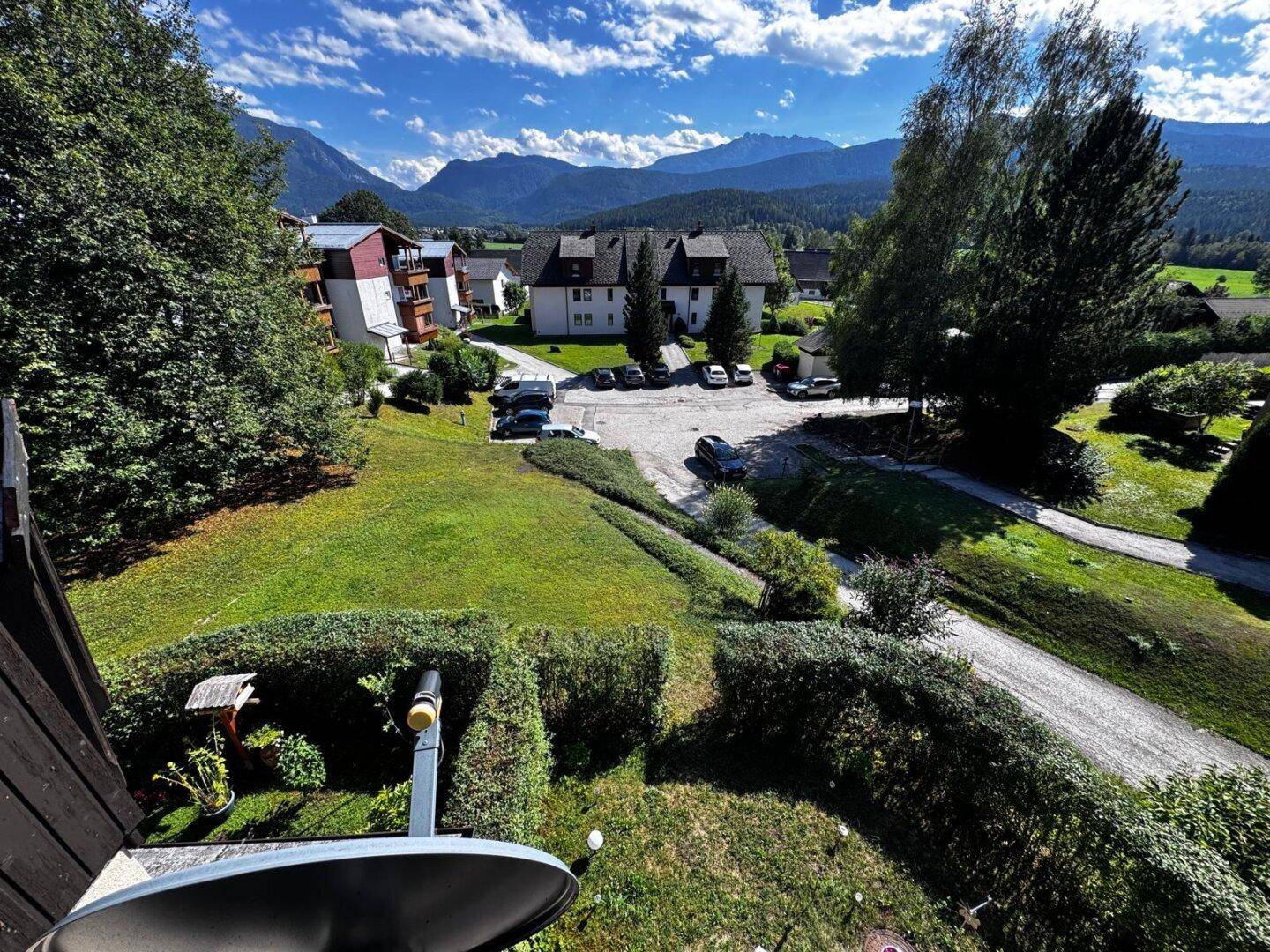 Weitläufiger Blick über die gepflegte Gartenanlage, Zufahrt und die umliegende Berglandschaft.