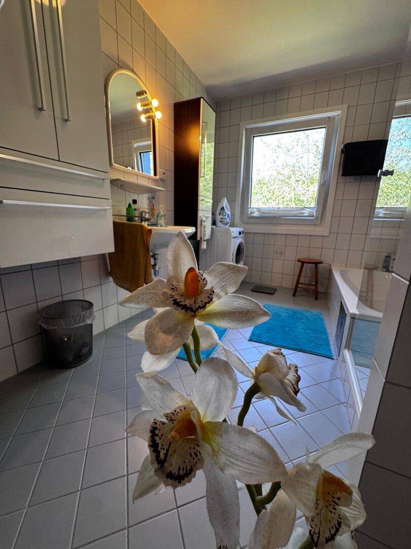 Funktionales Badezimmer mit Badewanne, Dusche, Waschbecken und Fenster für Tageslicht.
