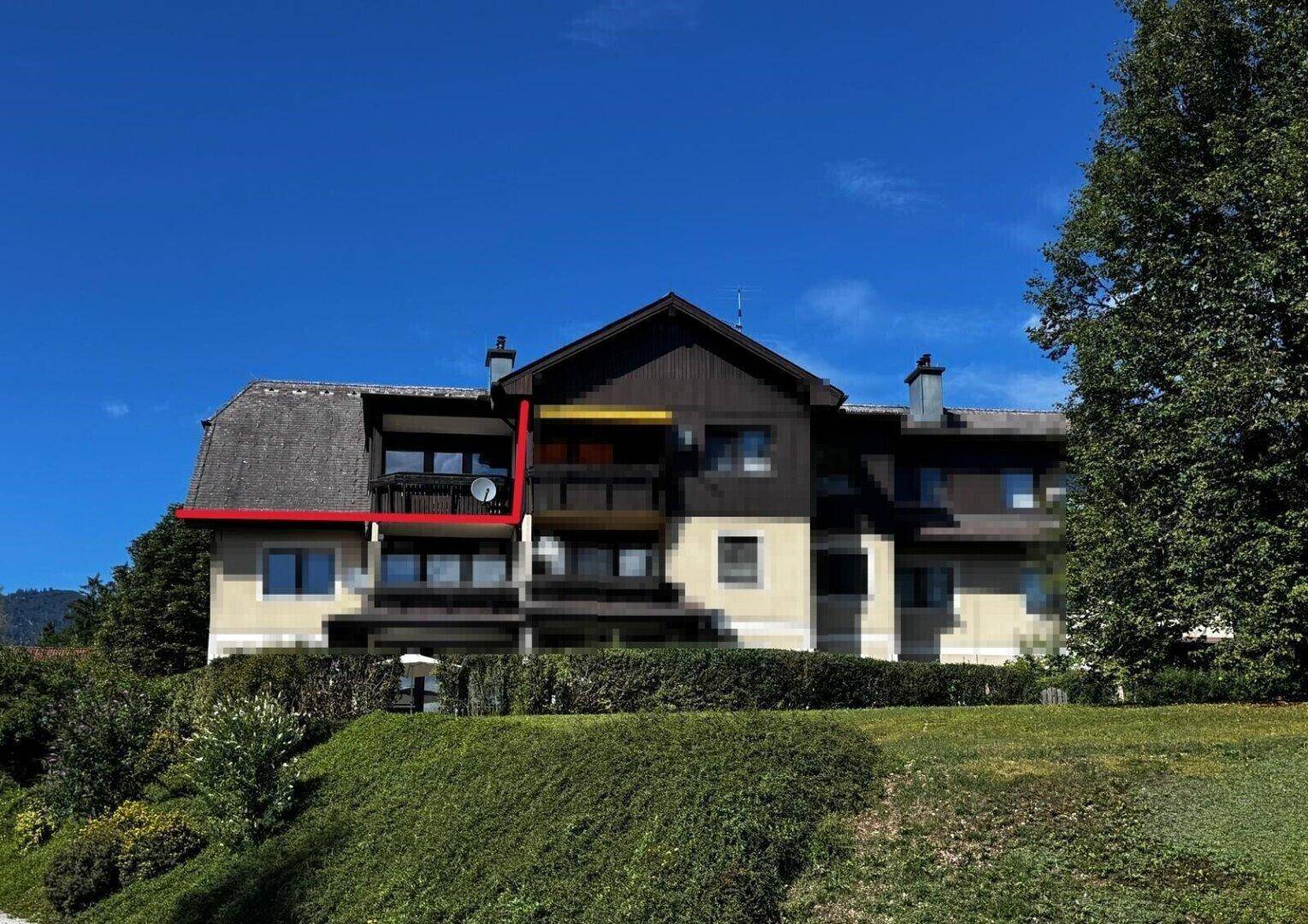 Ansicht der Gebäudefassade mit einem hervorgehobenen Balkon und umliegender gepflegter Grünfläche.