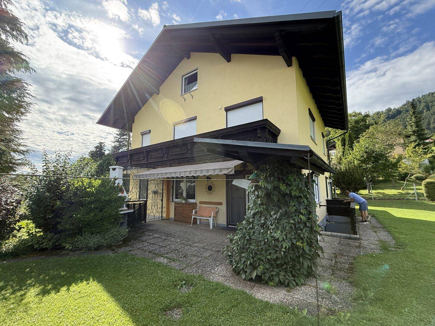 Rückseite des Hauses mit einer sonnigen Terrasse, Grillbereich und einem gepflegten Garten.