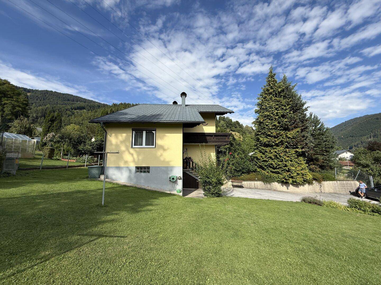 Seitenansicht des Hauses mit großem Garten und Blick auf die umliegende Natur und Berge.