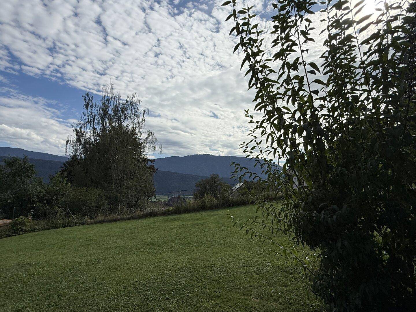 Weitläufiger Garten mit grüner Rasenfläche und malerischem Blick auf die Berglandschaft in der Ferne.