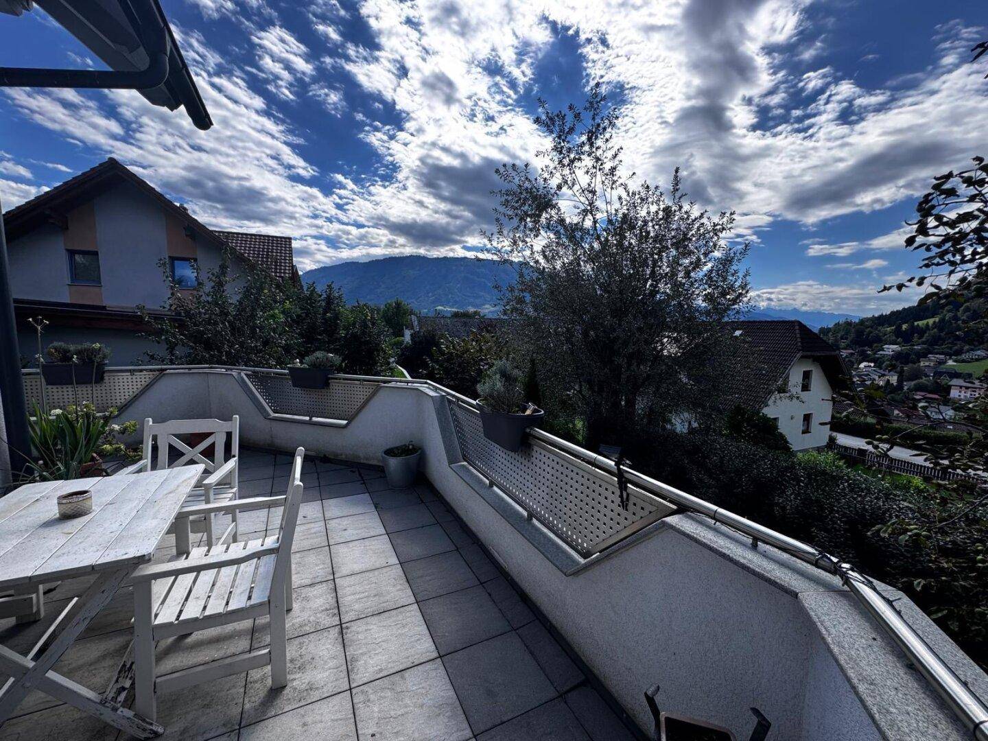 Sonnige Terrasse mit Panoramablick auf die Berge und die umliegende Natur unter blauem Himmel.