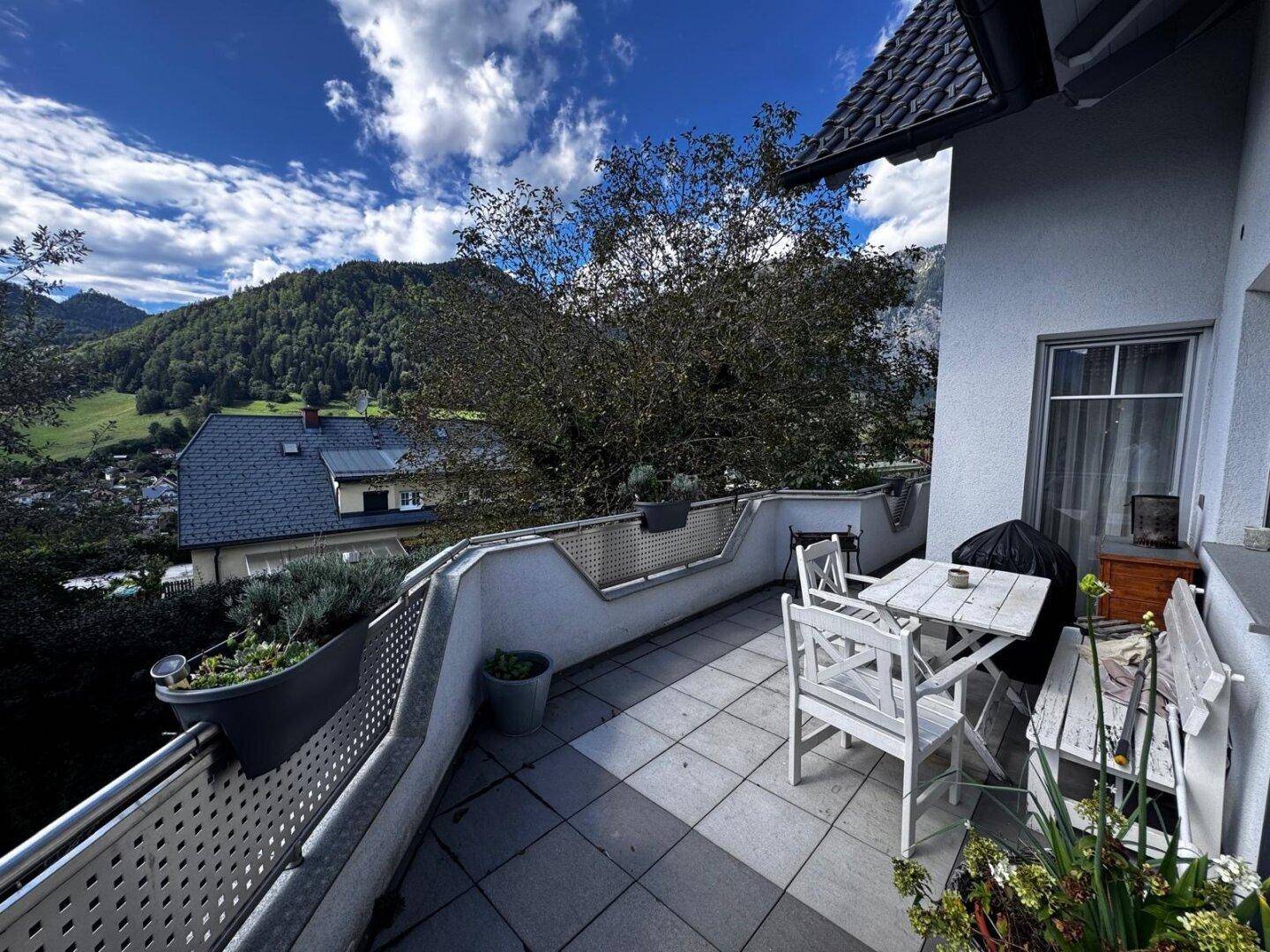 Geräumige Terrasse mit Sitzgelegenheiten, Fliesenboden und weitem Blick auf die grüne Berglandschaft.