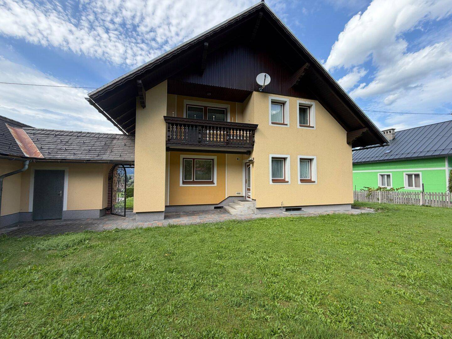 Vorderansicht des Hauses mit großem Rasen, Eingangsbereich und integrierter Garage.