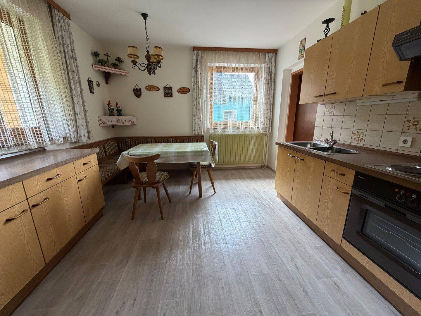Funktionale Küche mit Holzschränken, Essbereich und Blick auf die Nachbarschaft.