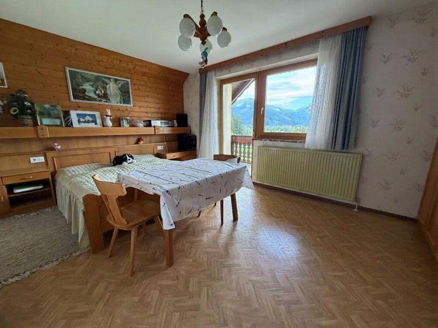 Schlafzimmer mit Holzwand, Doppelbett und direktem Zugang zum Balkon mit Bergblick.
