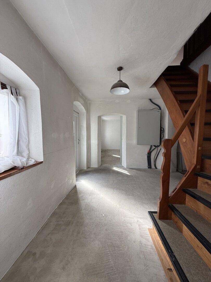 Heller Flur mit Holztreppe und natürlichem Lichteinfall, der auf weitere Renovierung wartet.