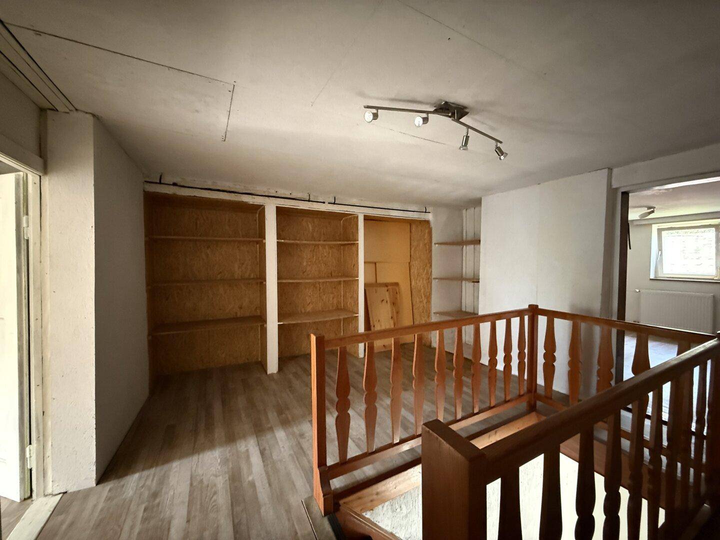 Offener Bereich im Obergeschoss mit Holzgeländer und eingebauten Regalen für Stauraum.