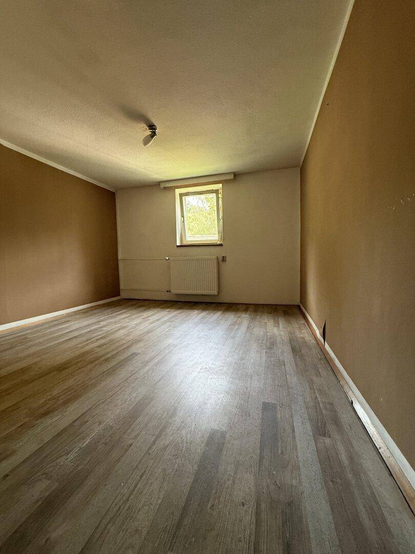 Schlafzimmer mit braunen Wänden, Laminatboden und einem Fenster für Tageslicht.