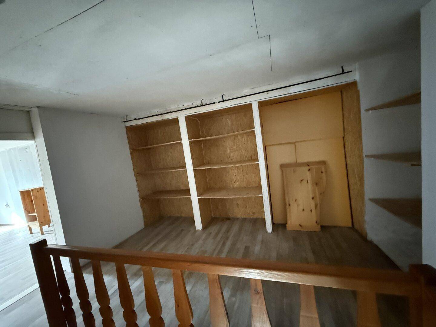 Offener Bereich im Obergeschoss mit Holzgeländer und eingebauten Regalen für Bücher.