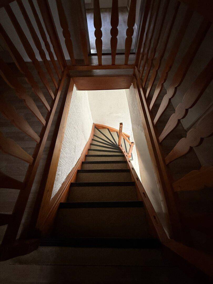 Holztreppe führt in ein tiefer gelegenes Stockwerk, mit natürlichem Lichteinfall von oben.