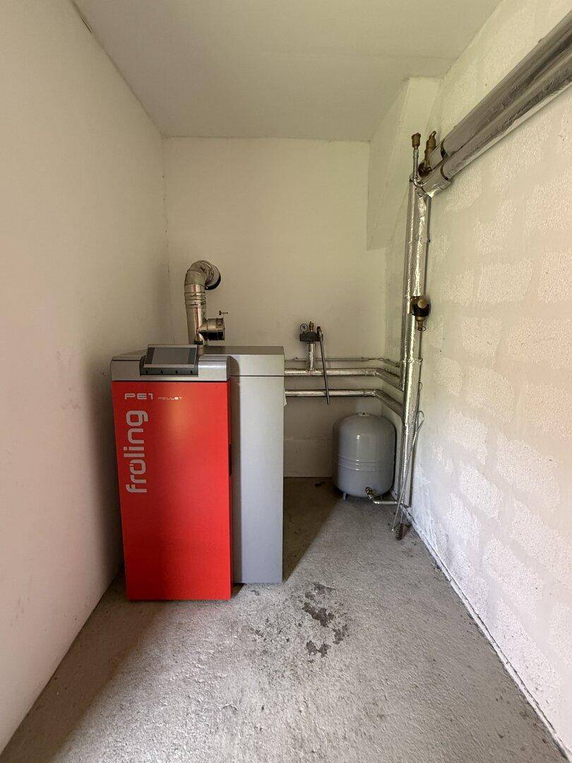 Heizraum mit einem modernen Froling Pelletkessel und Warmwasserspeicher für das Gebäude.