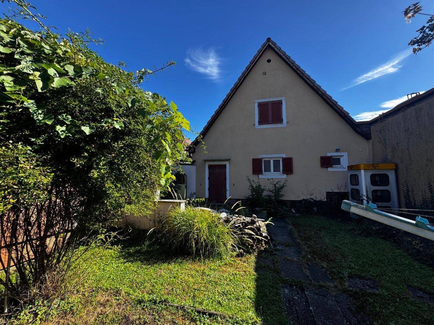 Seitenansicht des Hauses mit Gartenweg, umgeben von üppiger Vegetation und Sträuchern.