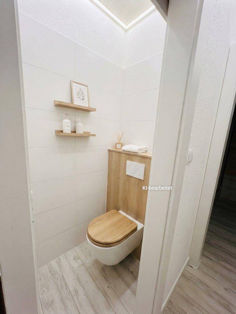 Kleines Gäste-WC mit Holzdetails, Wand-WC und modernen Fliesen in heller Ausführung.