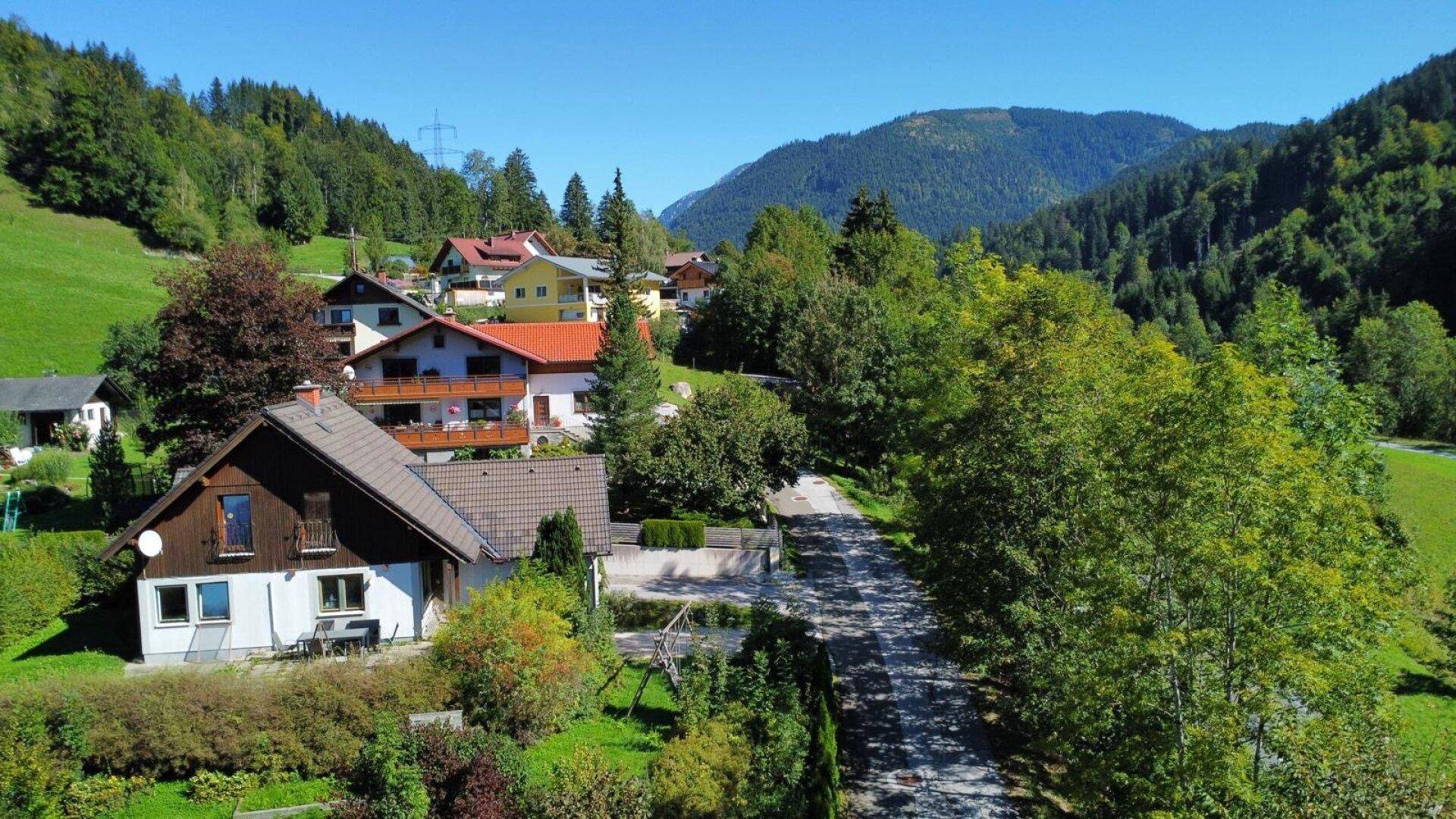 Haus in idyllischer Berglandschaft mit weitem Blick auf grüne Hügel und umliegende Häuser.