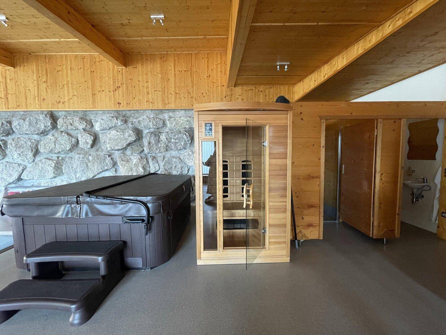 Innenbereich mit Whirlpool, Sauna und rustikaler Steinwand, ideal zur Entspannung und Erholung.