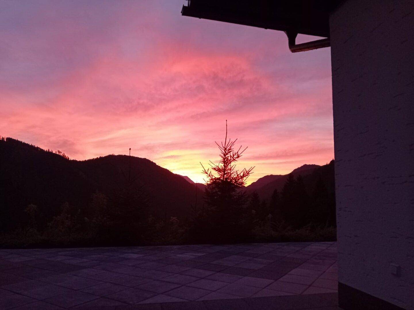 Atemberaubender Sonnenuntergang über den Bergen, von einer gepflasterten Terrasse aus gesehen.
