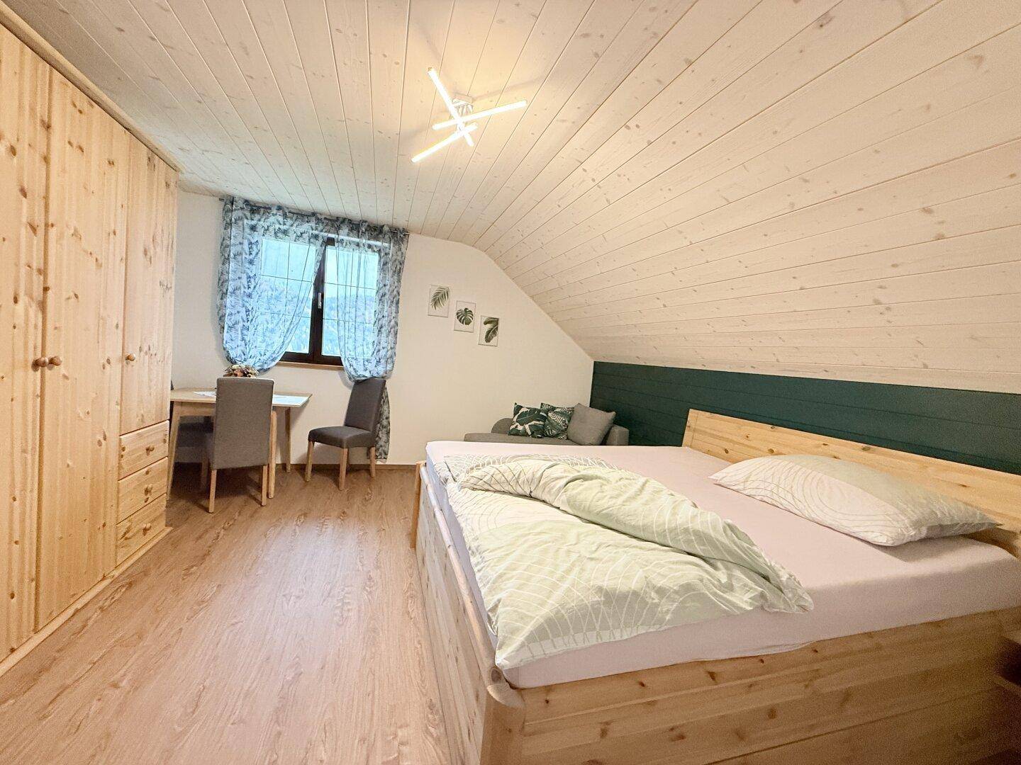 Gemütliches Schlafzimmer mit Holzbett, Einbauschrank und schräger Decke unter dem Dach.