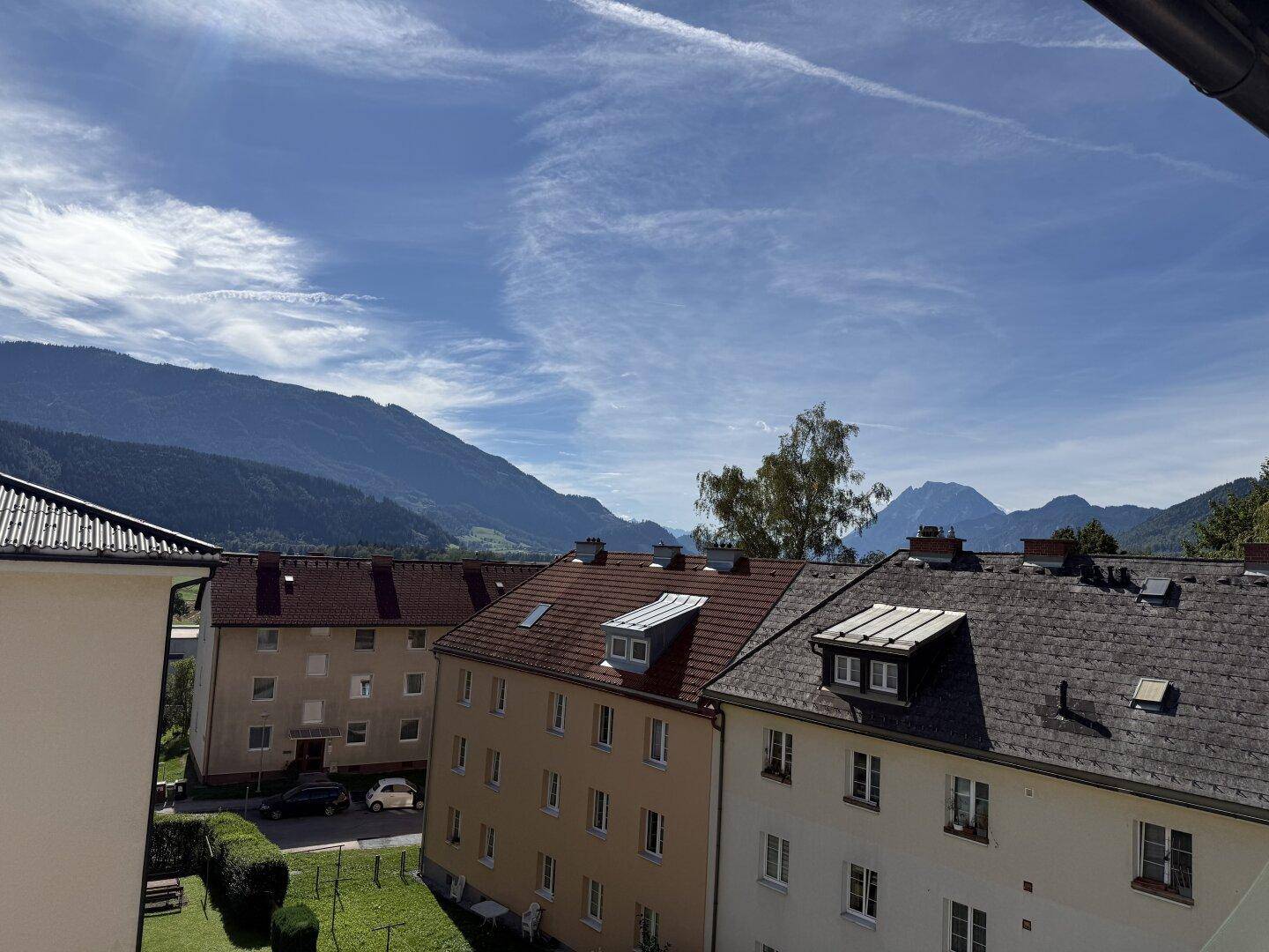 Weitläufiger Ausblick über die Dächer der umliegenden Häuser und die beeindruckende Berglandschaft am Horizont.