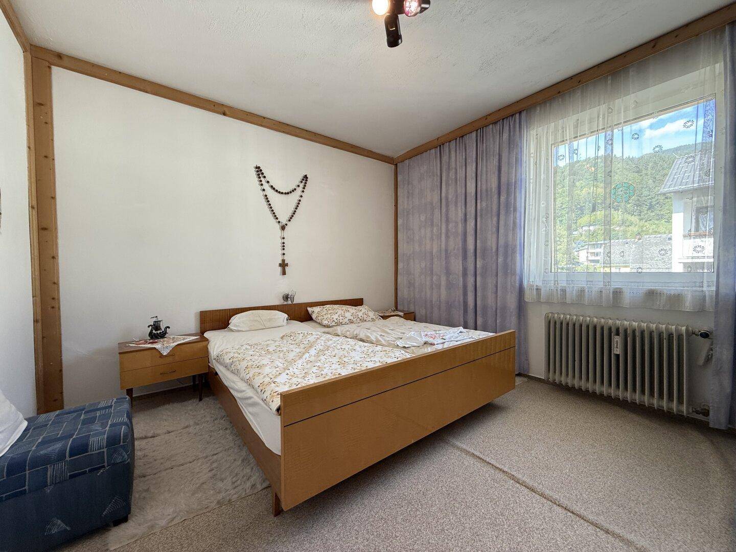 Geräumiges Schlafzimmer mit Doppelbett, Teppichboden und Holzvertäfelung an den Wänden, bietet eine ruhige Atmosphäre.