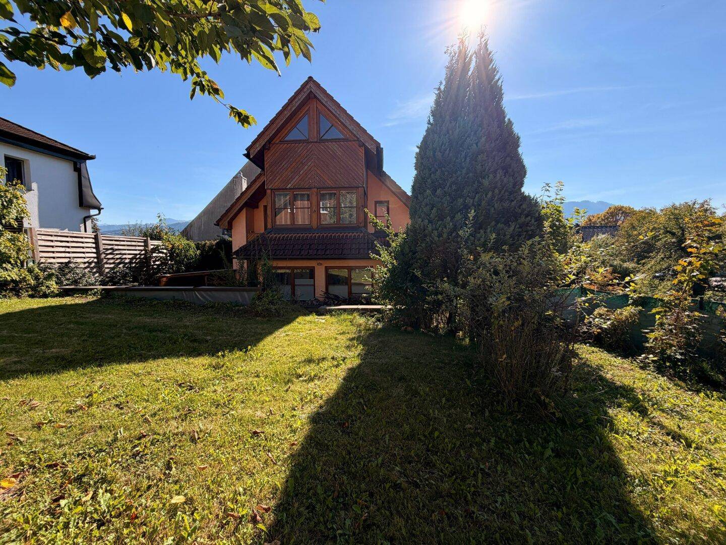 Sonnenbeschienenes Haus mit Holzfassade und weitläufigem Garten in ländlicher Umgebung.