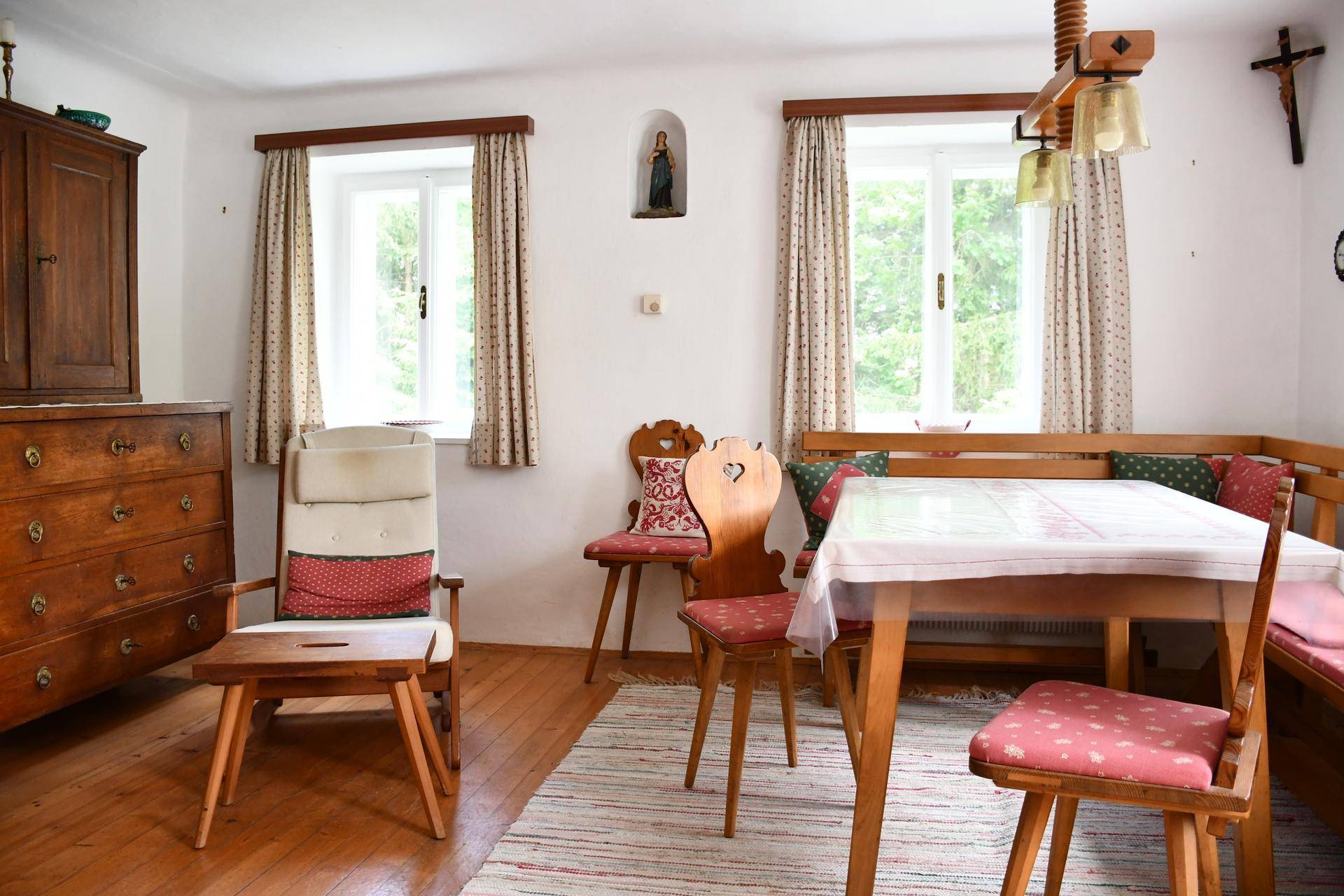 Gemütlicher Wohn-Essbereich im Landhausstil mit Holzboden und traditionellen Möbeln.