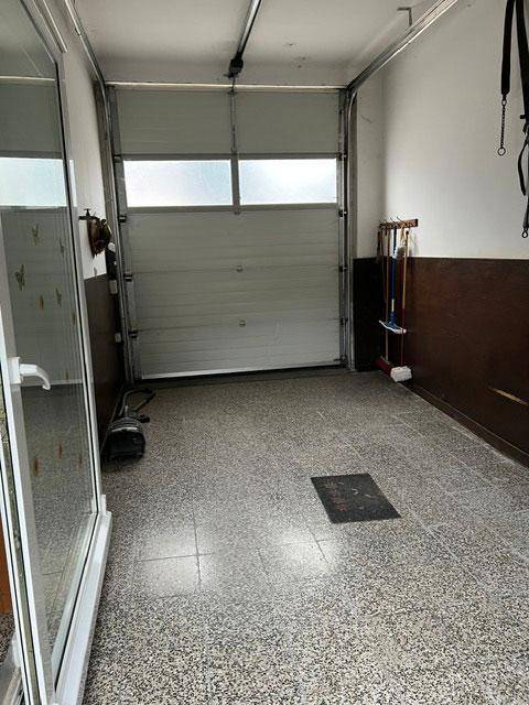 Garage mit Rolltor und gefliestem Boden, bereit für Fahrzeuge.