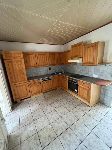 Küche im Landhausstil mit Holzschränken, Fliesenboden und integrierten Geräten.