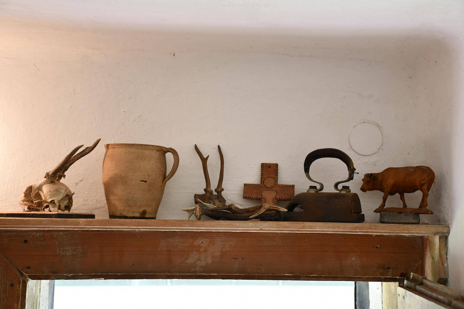 Eine Sammlung traditioneller Dekorationsgegenstände, darunter Geweihe und Keramik, auf einem Holzregal.