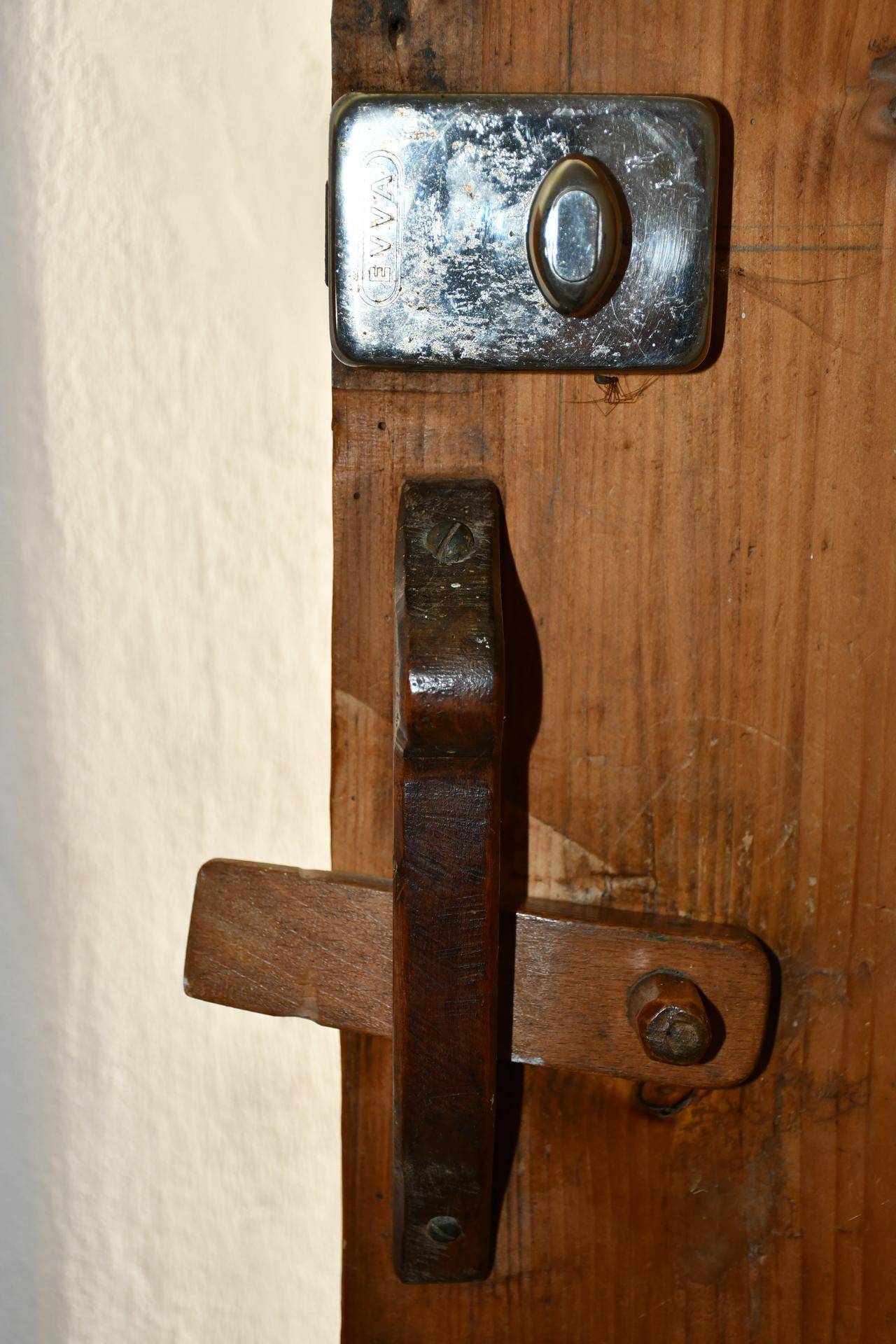 Nahaufnahme eines alten, rustikalen Türschlosses aus Metall und Holz an einer einfachen Holztür.
