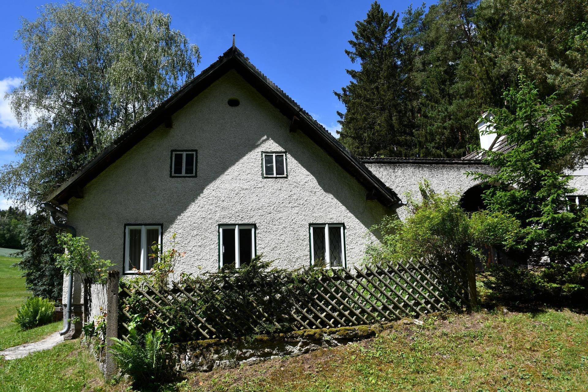 Vorderansicht eines traditionellen Landhauses mit weißer Fassade und mehreren Fenstern.