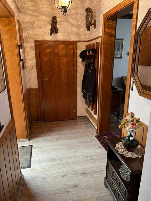 Flur mit Holzvertäfelung, Garderobe und hellem Laminatboden.