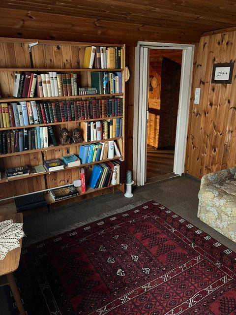 Zimmer mit großer Bücherwand, Holztäfelung und Teppichboden.