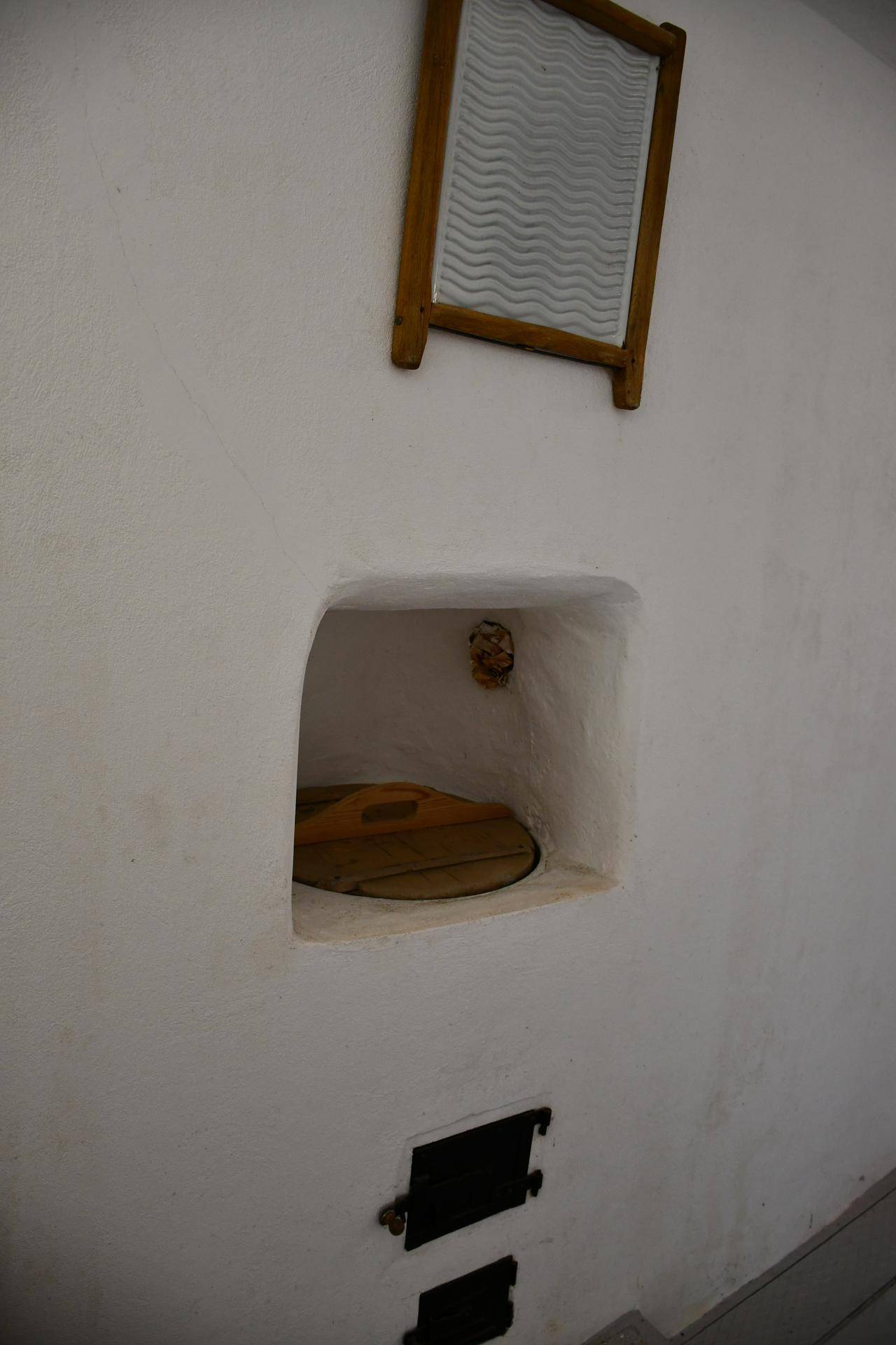Eine weiße Wand mit einer Nische und einem alten Waschbrett als Dekoration.