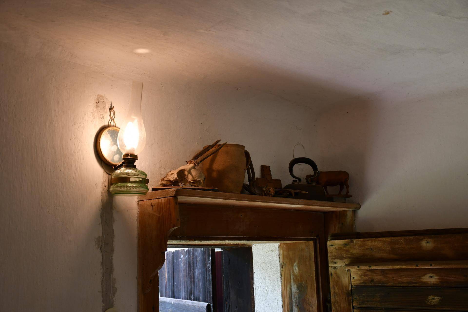 Rustikale Dekorationen und eine Petroleumlampe über einem Türrahmen in einem traditionellen Interieur.