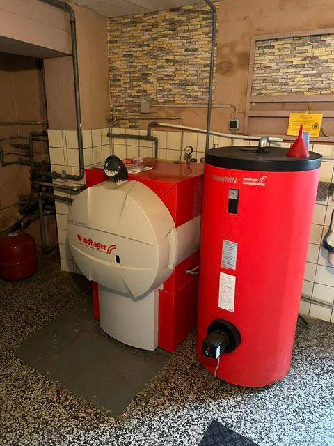 Heizungsraum mit modernem Heizkessel und Warmwasserspeicher im Keller.