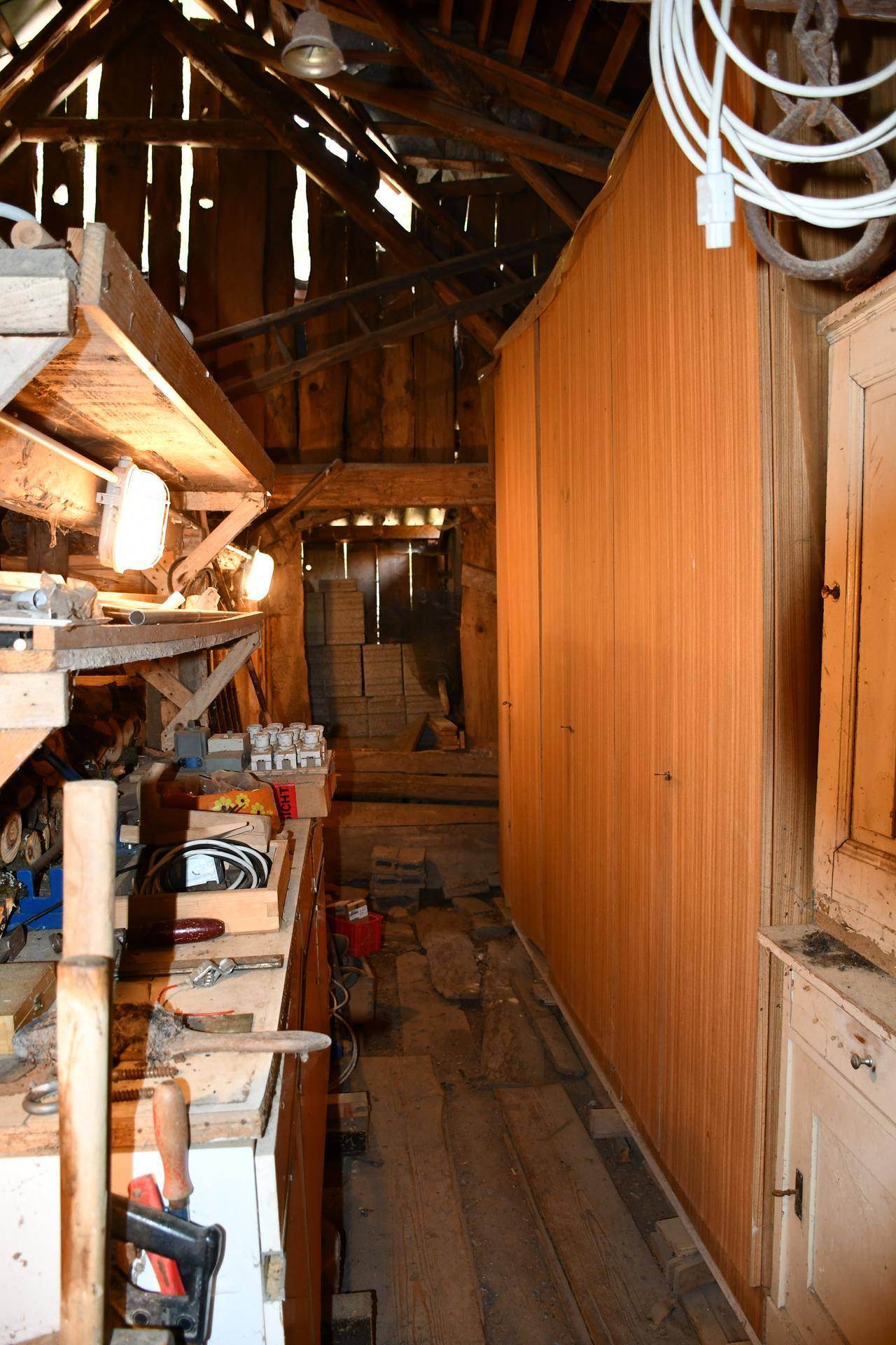 Werkstattbereich mit Werkzeugen, Holzregalen und sichtbaren Holzbalken, ideal für handwerkliche Arbeiten.