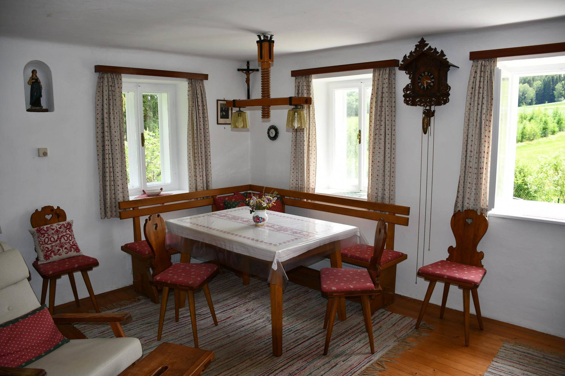 Traditioneller Wohn-Essbereich mit Eckbank, Holztisch und Blick ins Grüne.