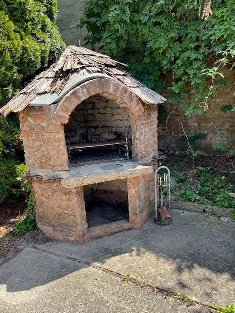 Gemauerter Grill im Gartenbereich mit Ziegeln und einem kleinen Holzdach.