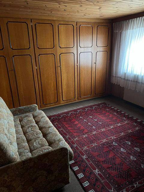 Schlafzimmer mit großen Einbauschränken aus Holz, Teppich und Vorhängen.